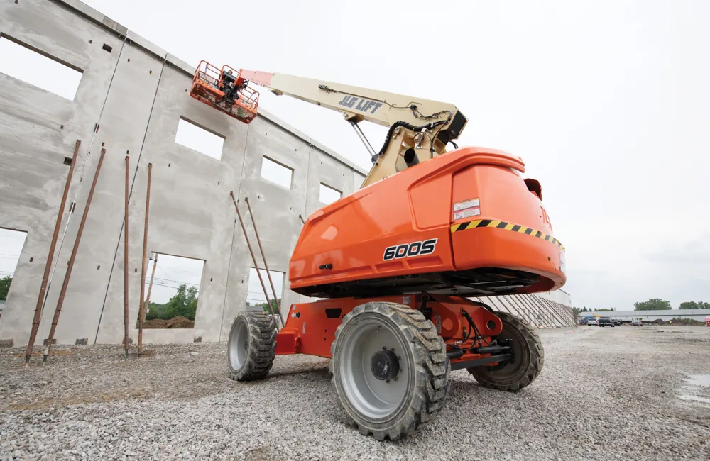 Plataforma articulada JLG em canteiro de obras com piso de cascalho