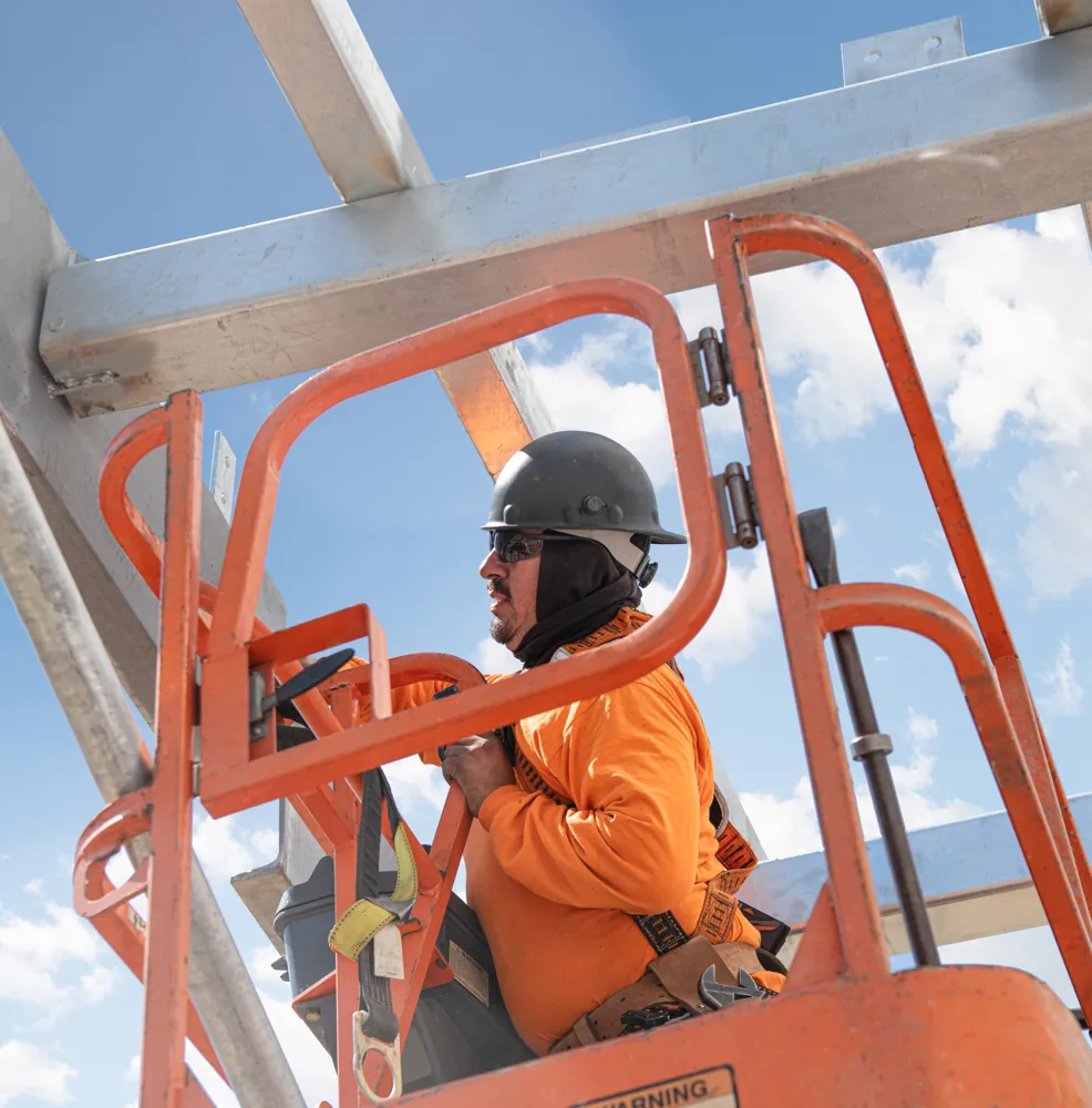 Operador com equipamento de proteção no cesto de plataforma elevatória JLG em obra