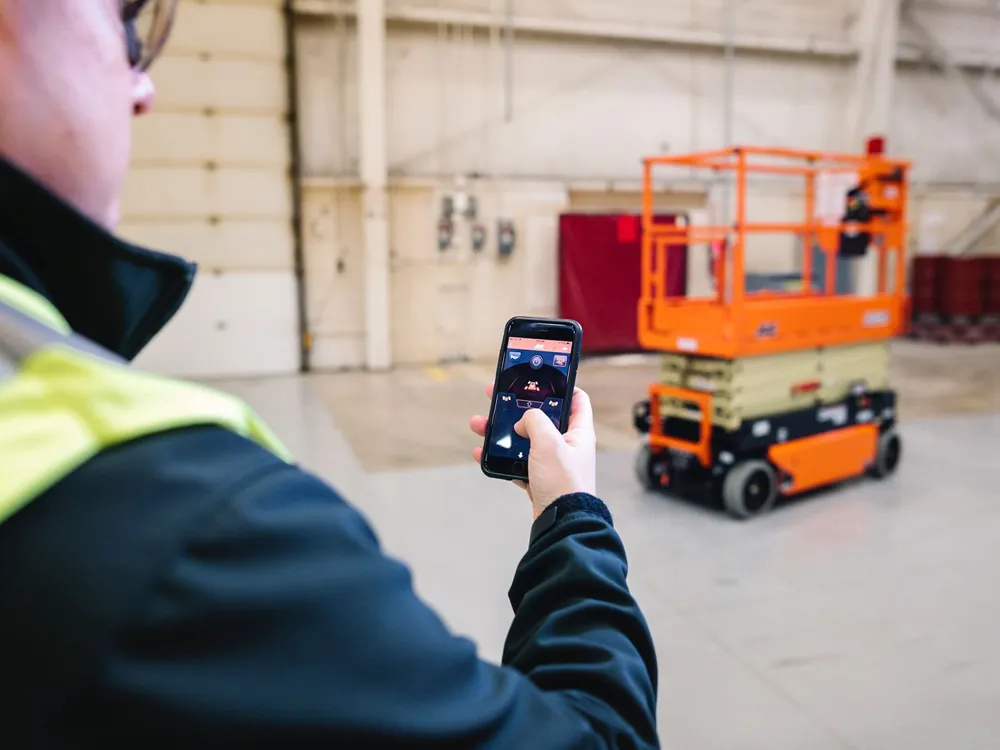 Profissional conferindo dados de plataforma tesoura JLG no celular