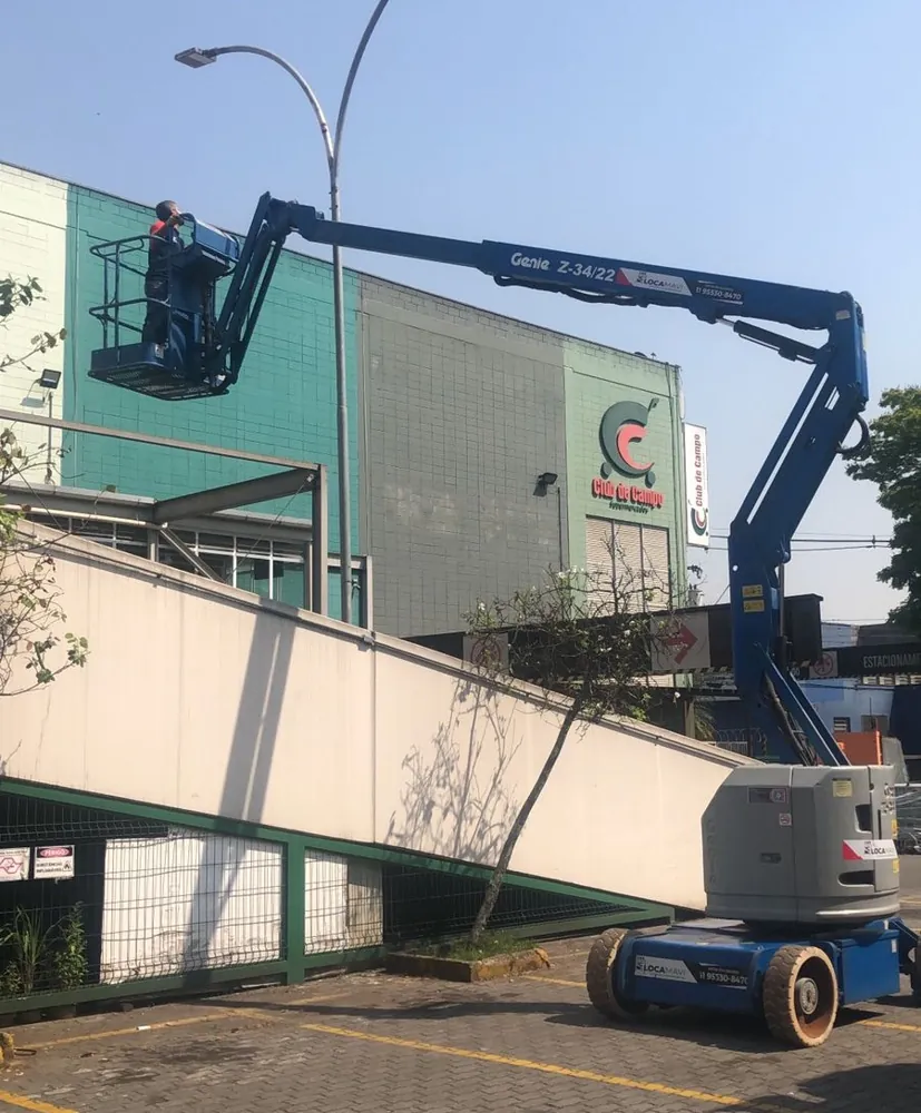 Plataforma articulada posicionada junto à fachada e à rampa de acesso de um edifício